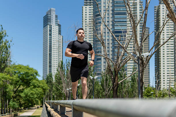 istock Latin man running in a park surrounded by modern skyscrapers 2209225930