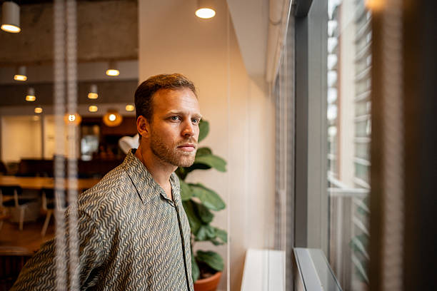 istock Businessman contemplating looking through the window at the office 2209227969