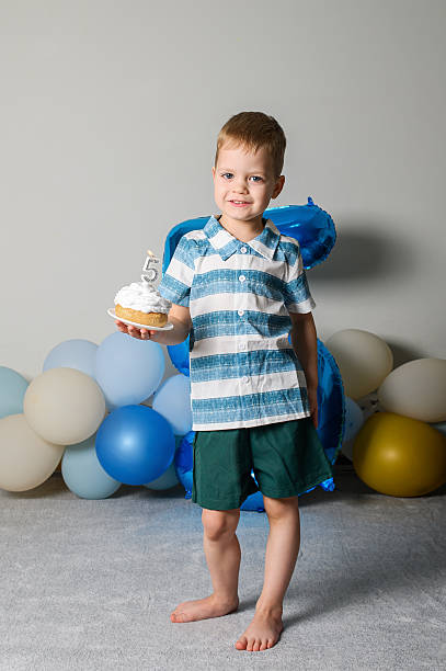 Happy Five Year Old Boy Celebrating Birthday with Cupcake and Candle