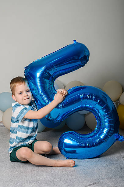 istock Happy Five Year Old Boy with Number Five Balloon 2209232997