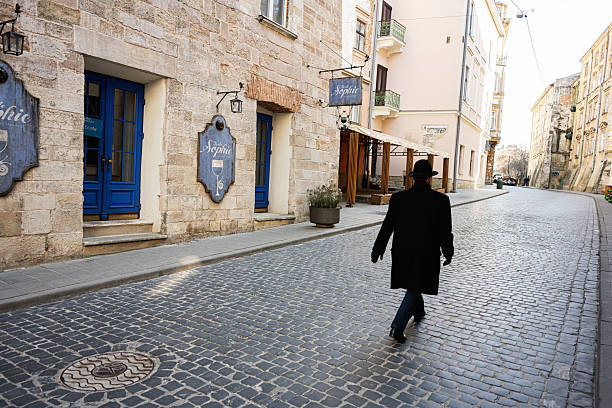 Lviv, Ukraine - April 07, 2025: Pedestrian solid man walking on a cobblestone street near a cafe in Lviv, Ukraine