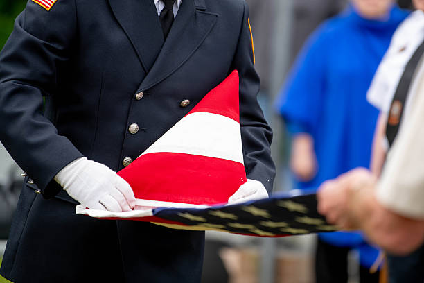 US military officers fold an American flag during a flag  folding ceremony on a national holiday such as Memorial Day or Veterans Day or at a military funeral.