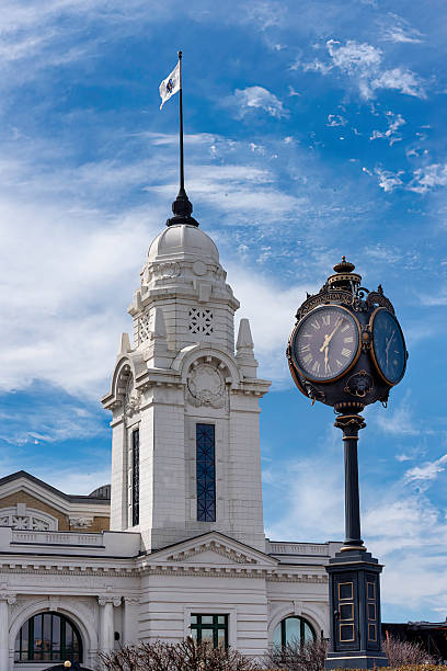 historic transportation hub located at 2 Washington Square in the heart of downtown. It serves as a terminal for both Amtrak and Massachusetts Bay Transportation Authority (MBTA) commuter rail services, connecting Worcester to Boston and other destinations.The current Union Station opened on June 4, 1911, replacing an earlier station built in 1875. Designed by the architectural firm Watson & Huckel in a French Renaissance Revival style, the station featured two prominent white marble towers flanking the main entrance. These towers were removed in 1926 due to structural concerns.Passenger services declined throughout the 20th century, leading to the station's closure in 1974. The building fell into disrepair but was added to the National Register of Historic Places in 1980. A comprehensive restoration was completed between 1994 and 2000, culminating in a grand reopening with a gala ball in 1999. ​Seen here, one of the two towers of Union Station appears behind the large clock in the landscaped roundabout at Washington Place.