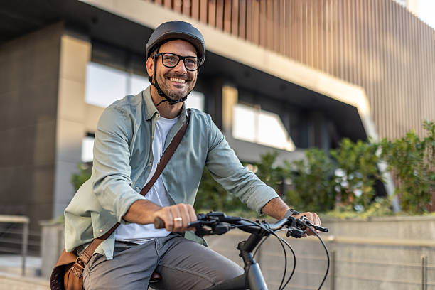 istock Smiling businessman riding bicycle in urban setting wearing helmet 2209249272