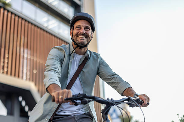istock Smiling businessman riding bicycle to work in urban setting 2209249925