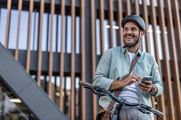 istock Smiling businessman using smartphone while riding bicycle in urban setting 2209251610