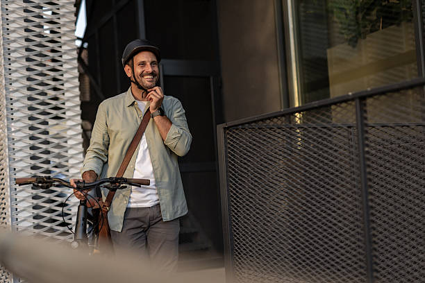 istock Smiling businessman removing helmet after cycling to work 2209251742
