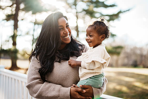 Loving mom holding joyful baby outside