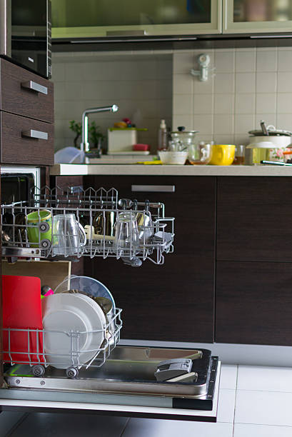 istock Open dishwasher filled with dishes. The messy kitchen background suggests real life and routine. Illustrates chores, home life, and modern appliances. 2209259812