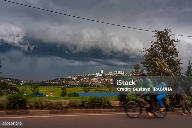 Cyclists On A Road In Kigali Under A Dramatic Sky Stock Photo - Download Image Now - Africa, African People, Architecture