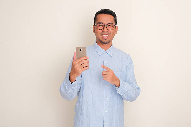 istock A man smiling and pointing at mobile phone that he hold 2209265764