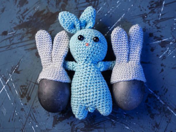 istock Happy Easter card. Knitted bunny toy holding two eggs with bunny ears , top view 2209270732