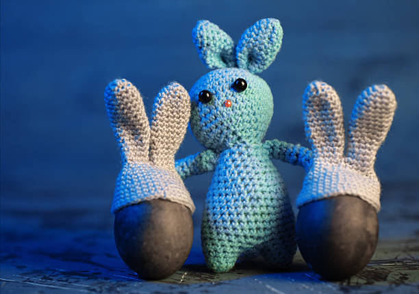 Knitted toy bunny and two Easter eggs with bunny ears hats. Copy space
