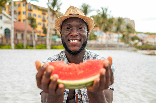 istock Joyful Young Man with Watermelon on Beach Vacation 2209270924