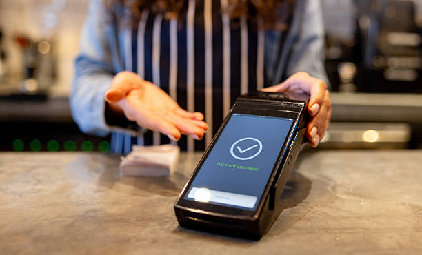 istock Coffee shop waitress pointing at a card reader showing a successful transaction 2209273755