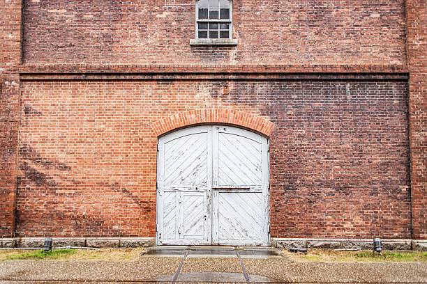 Rusty metal double doors set in weathered brick facade, evoking vintage urban charm amidst an aged cityscape.