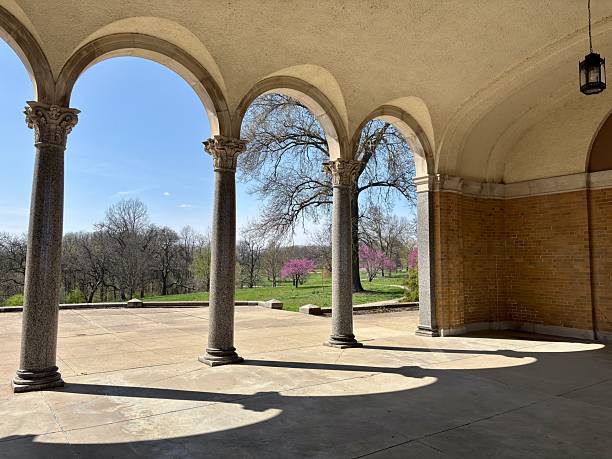 Shadows cast by arched pavilion onto spring lawn with blooming trees in Cincinnati, Ohio, United States