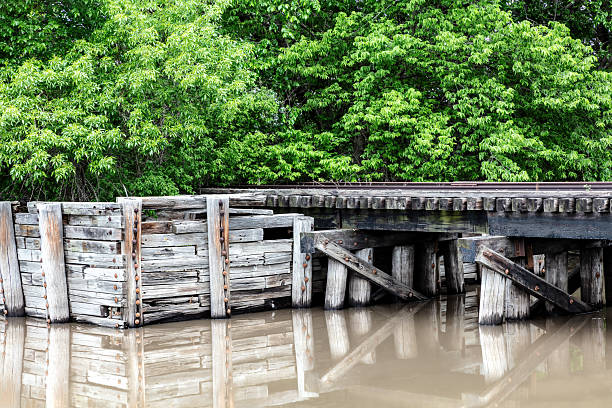 istock Wooden railroad trestle. Muddy pond with reflection. Trees in background. 2209275434