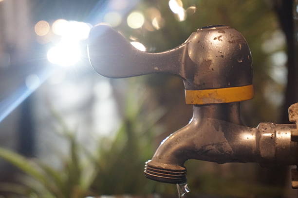Leaking outdoor faucet, night, garden bokeh