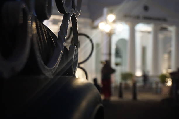 Nighttime ornate gate, colonial building, blurry people