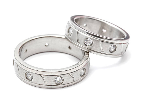 Silver wedding rings with diamonds, a symbol of commitment and love, on white.