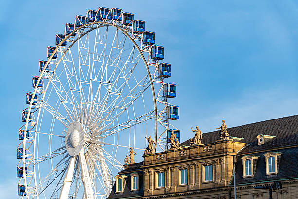 istock A striking Ferris wheel with blue gondolas rises beside a historic building 2209288108