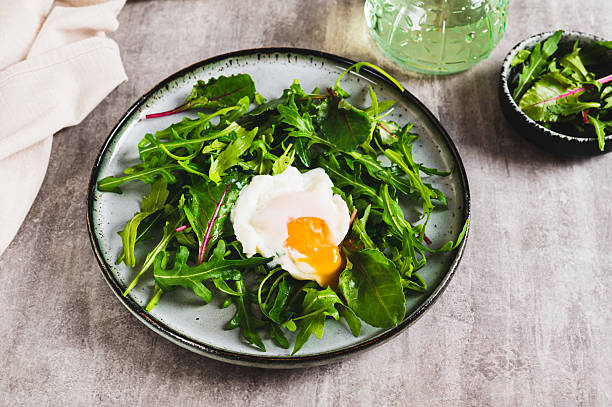 istock Leafy greens and poached egg on a plate on a table 2209292837