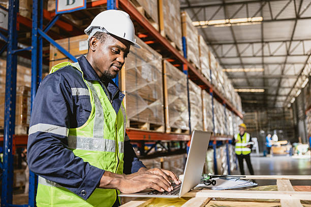 istock african black professional warehouse worker. stock inventory staff using computer check stock online 2209295341