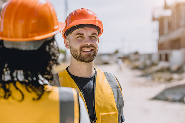 istock Construction worker happy smile. Engineer male wearing safety vest and helmet at construction site 2209295873