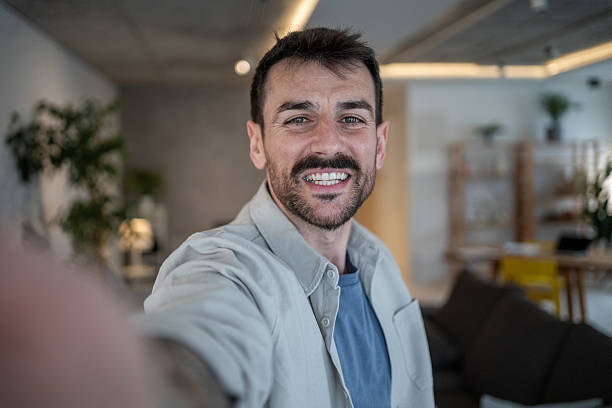 istock Happy man taking a selfie at home smiling at the camera 2209296969