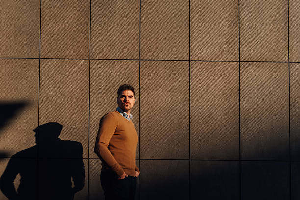 istock Businessman posing with hands in pockets against modern building wall 2209300605
