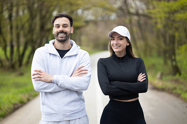 A cheerful couple stands by the path, showcasing their fitness enthusiasm and social connection during a sunny day outdoors.
