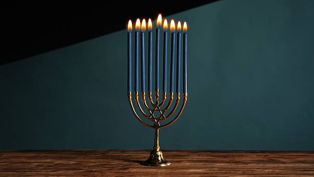 The warm atmosphere of the holiday table features an antique menorah with burning blue candles. This table setting embodies the spirit and traditions of Hanukkah.