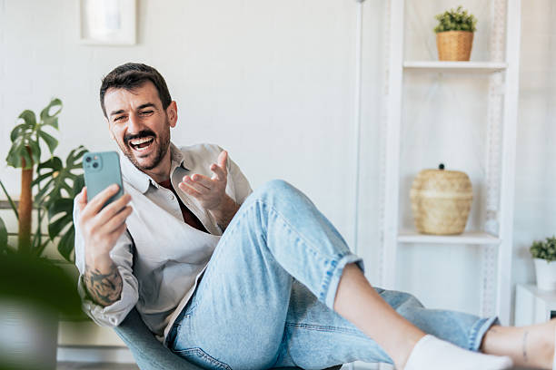 istock Man laughing while video calling with his smartphone at home 2209307933