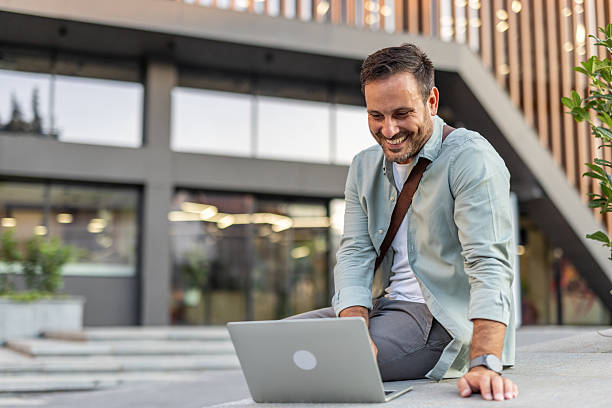 istock Cheerful businessman working with laptop outside office building 2209307951