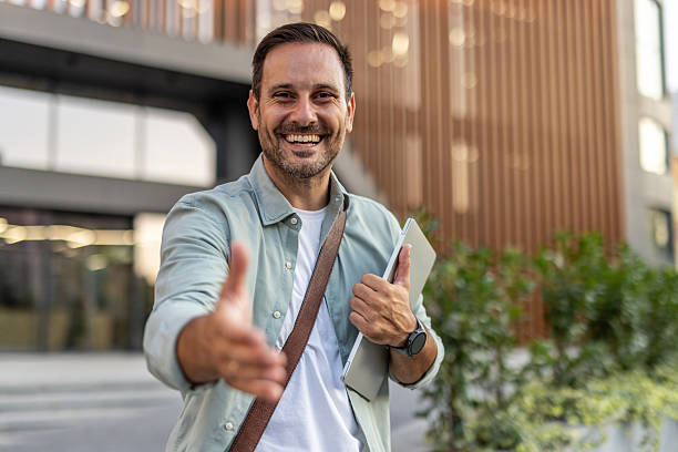 istock Smiling businessman offering handshake in front of office building 2209308220
