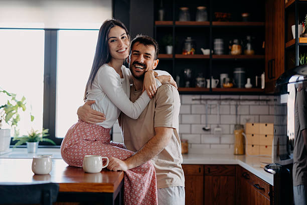 istock Happy couple embracing and smiling in kitchen at home 2209308749