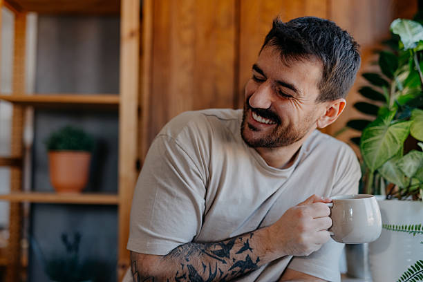 istock Young man smiling and drinking coffee at home 2209308771