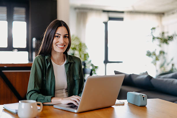 istock Young woman working from home, typing on a laptop and smiling 2209309863