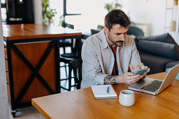 istock Focused man working from home using laptop and smartphone 2209310200