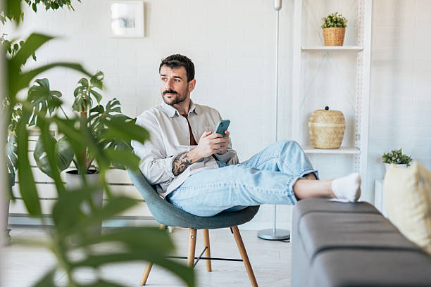 istock Man relaxing on armchair at home using his smartphone 2209310687