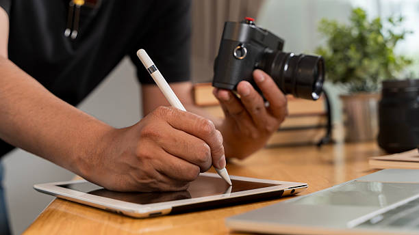 istock Close up of artistic hand using digital tablet and stylus while retouching image design at professional studio office desk. 2209310949