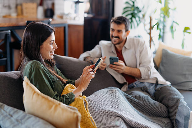 istock Young couple relaxing on the sofa, browsing their smartphones 2209311749