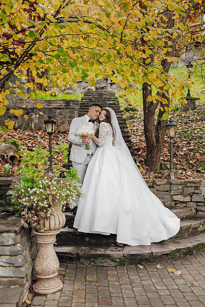 istock A bride and groom are posing for a picture in front of a tree 2209312029
