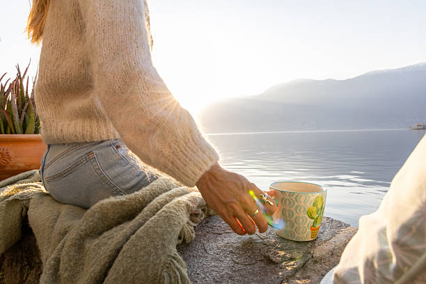 istock Woman Relaxing by Lakeside Holding Coffee Cup 2209312870