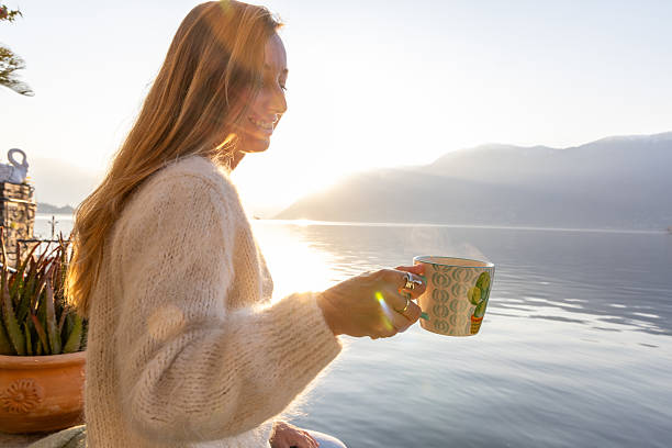 istock Woman Relaxing by Lakeside Holding Coffee Cup 2209312874