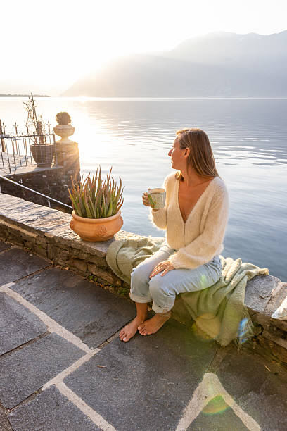 istock Woman Relaxing by Lakeside with Morning Sunlight 2209312904