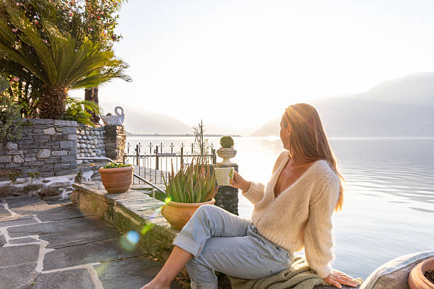istock Woman Relaxing by Lakeside with Morning Sunlight 2209312921