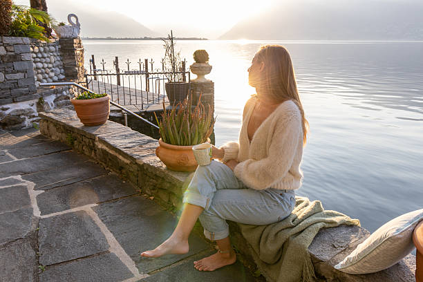istock Woman Relaxing by Lakeside with Morning Sunlight 2209312926