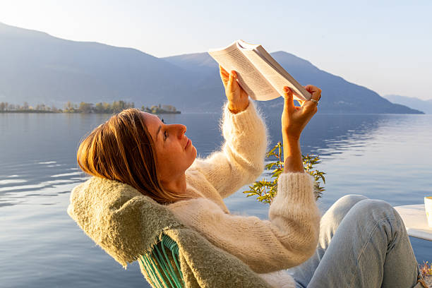 istock Woman Relaxing by Lakeside Reading a Book 2209313083